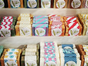 Rows of soap with labels on shelves, by Paradise Handmade Soap.